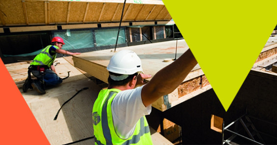 Construction site workers aiding the delivery of off-site timber panels 